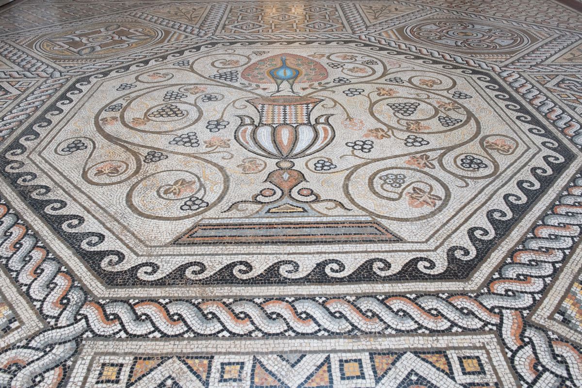 Mosaico pavimentale con pavone e motivi decorativi.