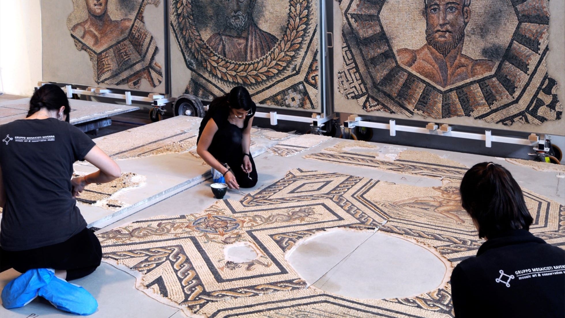 Mosaicisti che restaurano un mosaico pavimentale.