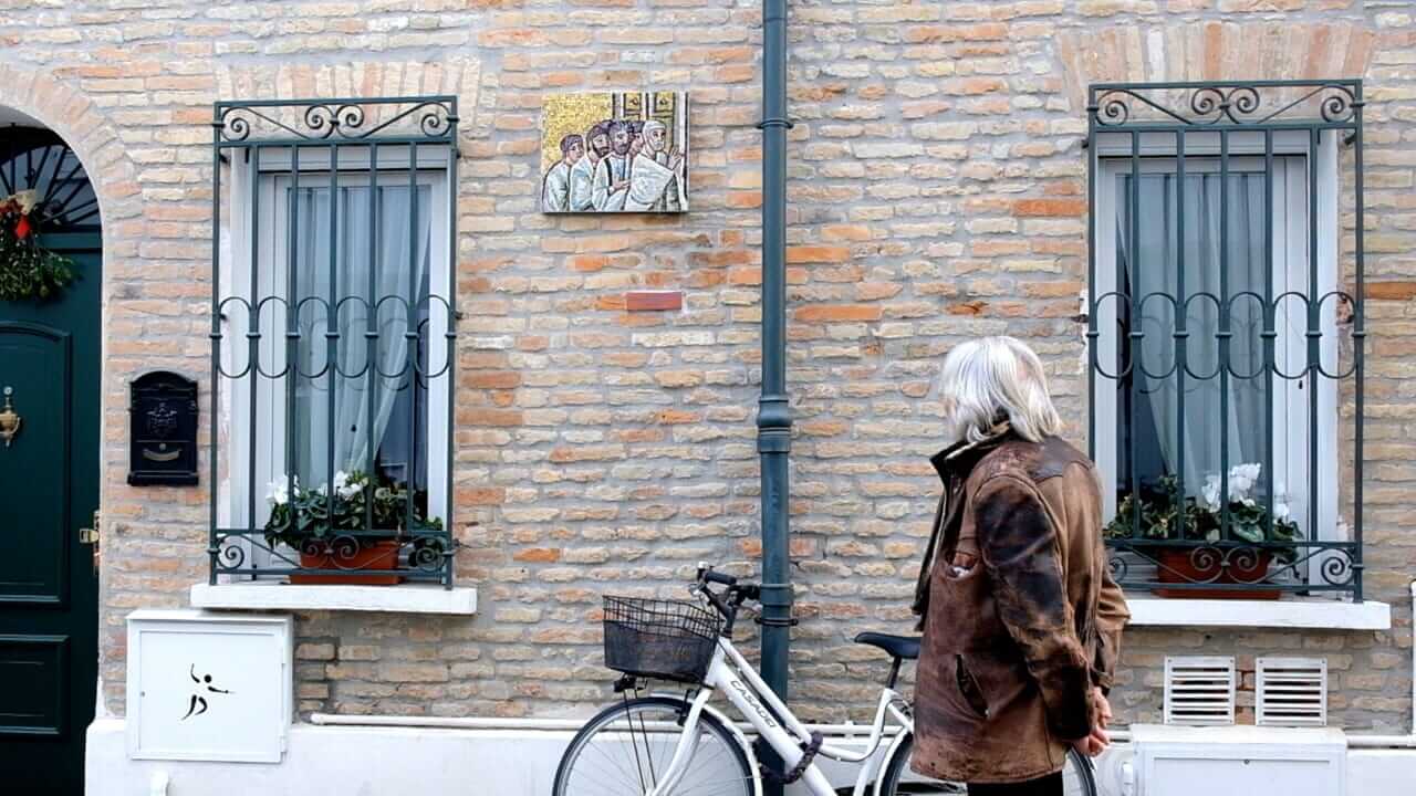 Foto di una persona che guarda un mosaico sulla facciata di una casa.